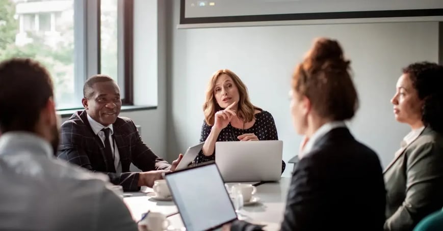 A group of meeting planners sitting around a desk discussing offsite planning