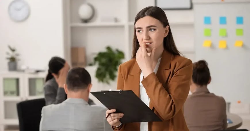 A nervous looking Executive Assistant biting her finger in a meeting room