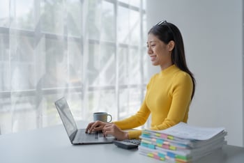 An Executive Assistant writing a meeting agenda on her laptop