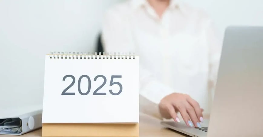 An Executive Assistant sitting in front of her computer with a 2025 calendar
