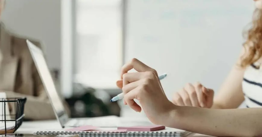 An Executive Assistant working at her desk, writing a simple meeting objective