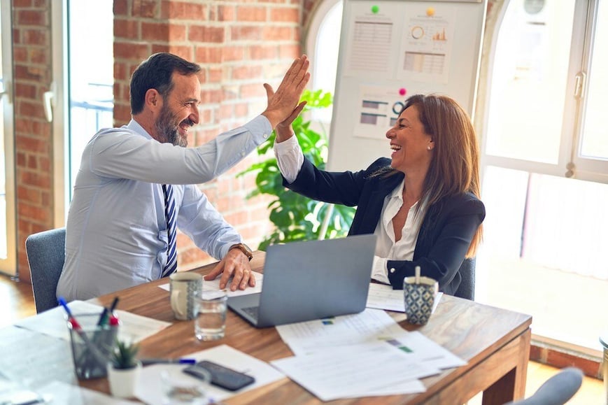 A male and female colleague high fiving in the office