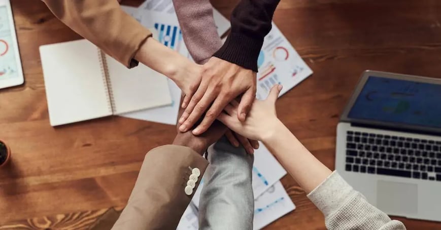 Team shaking hands after successfully booking an in-person meeting